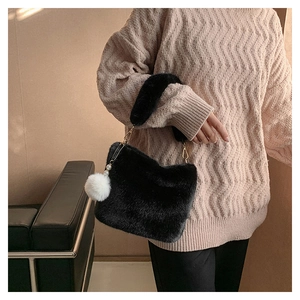 Detail of black plush bucket bag featuring soft faux fur and white pompom pearl pendant
