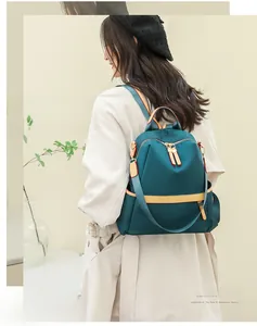 Side view of a teal water-resistant backpack with yellow accents worn by a model
