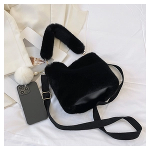 Detail shot of black faux fur bucket bag with plush ball charm and dual strap design