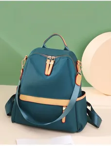 Detail of teal nylon backpack featuring yellow contrast stripes and dual metal zippers