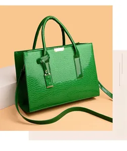 Detail of emerald green crocodile pattern tote bag with glossy finish and gold metal accents