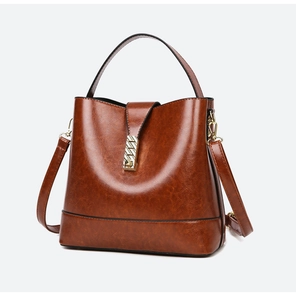 Detail of vintage brown bucket bag with oil wax leather texture and gold metal clasp