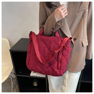 Detail view of red quilted tote bag with diamond stitching and adjustable strap