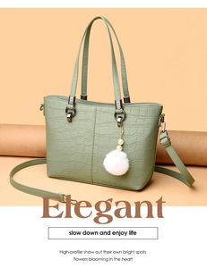 Detail view of morandi green bucket bag with crocodile texture and fuzzy pompom charm