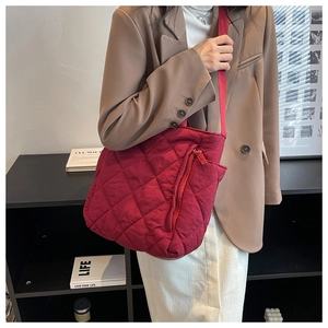 Detail of red quilted nylon tote bag with diagonal zipper pocket and wide shoulder strap