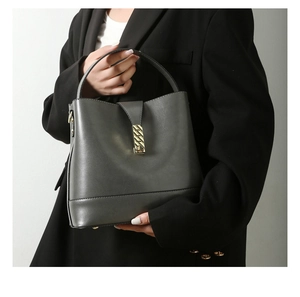 Close-up of gray structured leather handbag with elegant gold chain buckle and handle