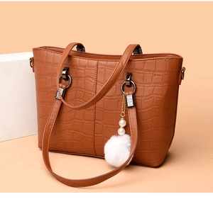 Detail of dark brown faux leather tote with crocodile pattern and plush pearl charm