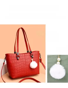 Close-up of red crocodile pattern bucket bag with soft white fur ball pendant and silver hardware