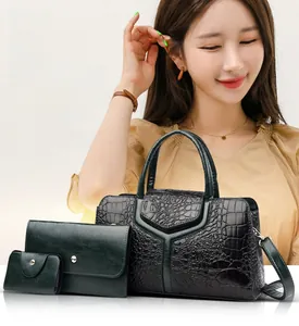Detail of dark green crocodile embossed tote bag set with three pieces and metallic hooks