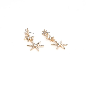 Detailed view of long gold star drop earrings featuring three tiers of sparkling crystals