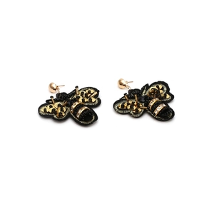 Close-up of handmade fabric bee earrings with gold sequins and beaded wings
