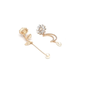 Goldene Blumen- und Mondohrringe asymmetrisch mit Perlen und Strass auf weißem Grund