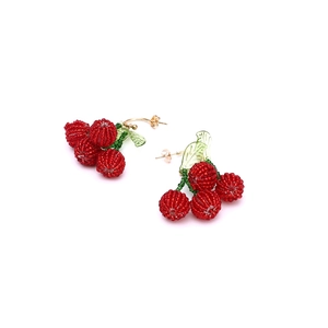 Close-up of handmade beaded cherry earrings with red berries and green leaves