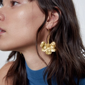 Vintage gold metal flower drop earrings with layered petals on a female model