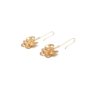 Macro detail of golden flower earrings featuring brushed metal petals and intricate pistils