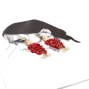 Macro view of fish-shaped drop earrings featuring golden hammer metal and red sequins