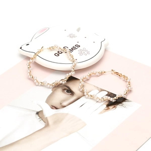 Elegant gold metal hoop earrings with woven white pearls in a large circular design