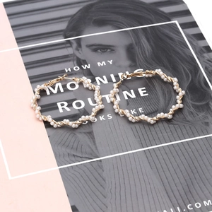 Exaggerated golden geometric hoop earrings wrapped with pearls on a fashion magazine background