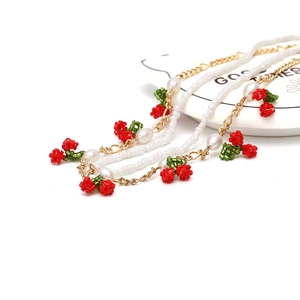 Multilayer beaded cherry necklace with white pearls and gold chain on white background