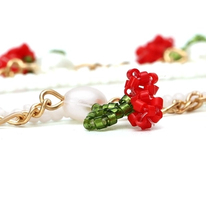Close-up of handmade beaded cherry pendants with red seed beads and white pearls