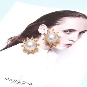 Boucles d'oreilles dorées avec perle centrale et cadre métallique à effet sunburst