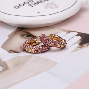 Détail de boucles d'oreilles en U dorées avec cristaux roses et rouges pavés