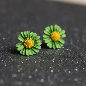Macro detail of daisy stud earrings featuring matte green petals and yellow textured centers