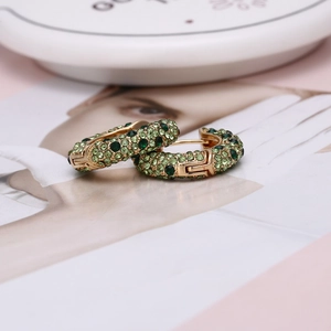 Vue détaillée de boucles d'oreilles en U dorées avec cristaux verts sertis pavé