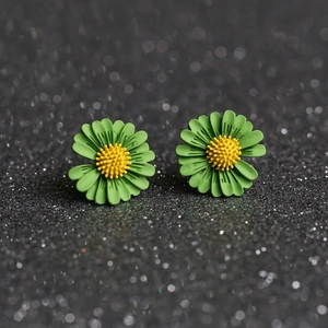 Detailed macro view of green and yellow daisy earrings on a shimmering dark background