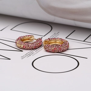 Détail des boucles d'oreilles en U dorées avec micro-pavage de strass roses fins