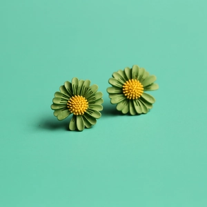 Detailed view of daisy stud earrings with green petals and yellow center on mint background