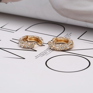Gros plan détaillé de boucles d'oreilles U dorées avec strass et perles blanches
