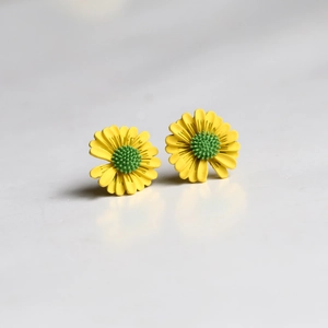 Macro detail of yellow daisy stud earrings with green center and fine floral textures