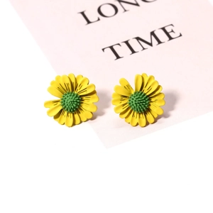 Detailed view of yellow daisy flower stud earrings with green center on pink card