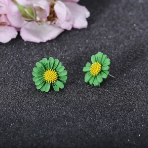 Detailed macro shot of small green daisy stud earrings with yellow 3D textured centers