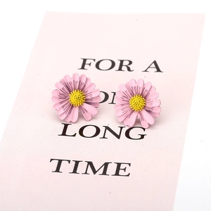 Close-up of pink daisy stud earrings with yellow pistils on a matching pink card