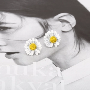 Detail of colorful daisy earrings on a creative magazine background for a realistic visual effect