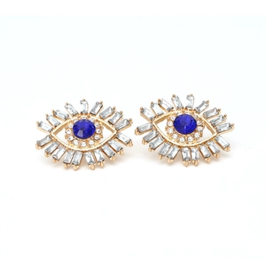Macro view of gold devil's eye earrings with blue center stone and crystal eyelashes