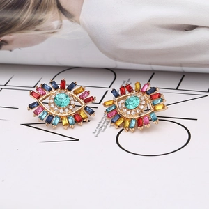 Exaggerated Evil Eye stud earrings with colorful rhinestones on a fashion magazine