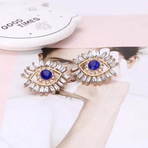 Macro detail of gold evil eye earrings with blue stones and radiant zircon fringe