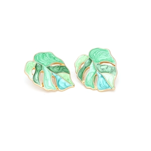 Macro detail of tropical monstera leaf earrings with colorful enamel and gold finish