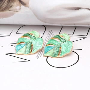 Macro detail of Monstera leaf earrings with colorful enamel gradient and golden alloy edges