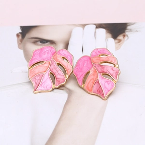 Close-up of pink and orange enamel monstera leaf earrings with gold-toned metal borders