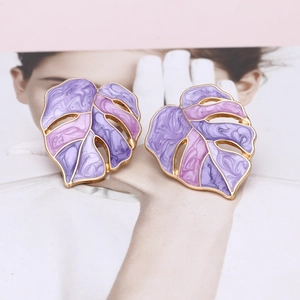 Detail of tropical monstera leaf earrings with pink marble enamel inlay and gold plating