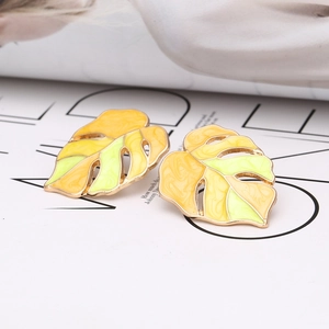 Detail of Monstera leaf earrings with yellow and green enamel on gold plating