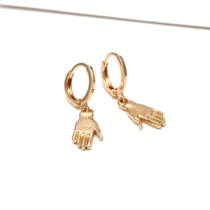 Gros plan sur les boucles d'oreilles baroques dorées avec pendentif main détaillé