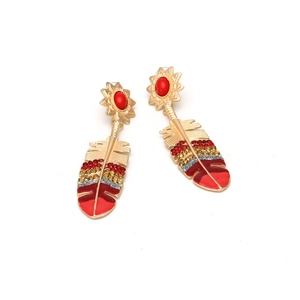 Detailed close-up of feather earrings with red rhinestones and gold alloy metal base