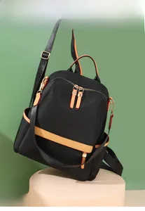 Close-up of black nylon backpack with light brown leather trim and golden hardware accents