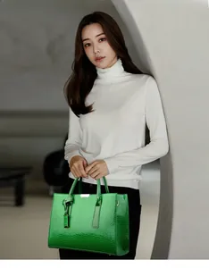 Detail of bright green crocodile embossed tote bag held by a model in a minimalist setting