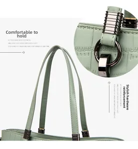 Detail of mint green crocodile pattern bag with reinforced round metal rings and dual handles